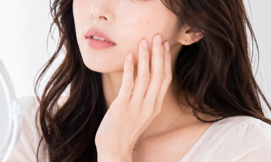 鏡で顔のほくろをチェックしている女性
